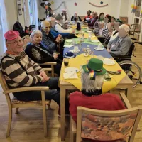 viele Bewohner und Bewohnerinnen sitzen am bunt geschmückten Tisch
