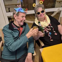 zwei Bewohner:innen stoßen mit Getränken an