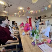 Ein Mann steht, viele Personen sitzen am Tisch