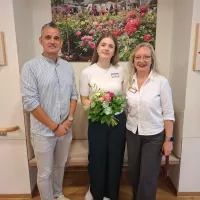 Drei Personen vor einem Blumenbild