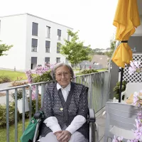 Bewohnerin auf dem Balkon mit Blumen