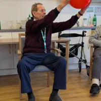 Ein Bewohner hebt einen roten Ball nach oben