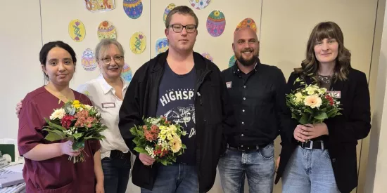 fünf Personen stehen vor einer Wand mit Osterdeko
