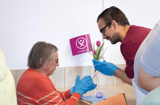 Bewohnerin und Betreuer malen Ostereier an