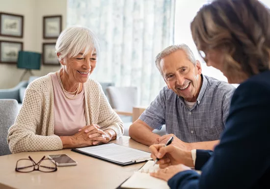 3 Menschen sitzen am Tisch und unterhlaten sich.